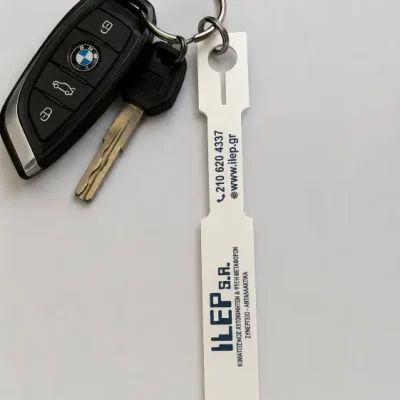 Λευκό χάρτινο μπρελόκ σήμανσης κλειδιών συνεργείου αυτοκινήτων με εκτυπωμένο λογότυπο, περασμένο σε κλειδί.